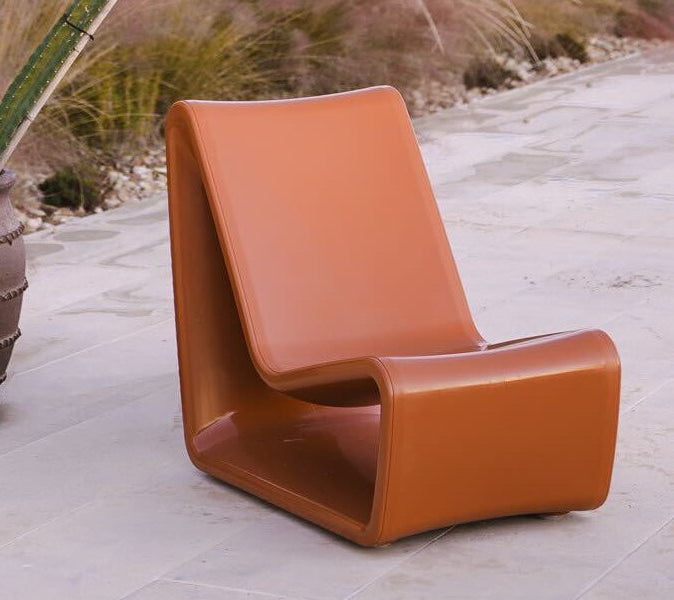 Brown chair on a patio with a gazebo and plants in the background