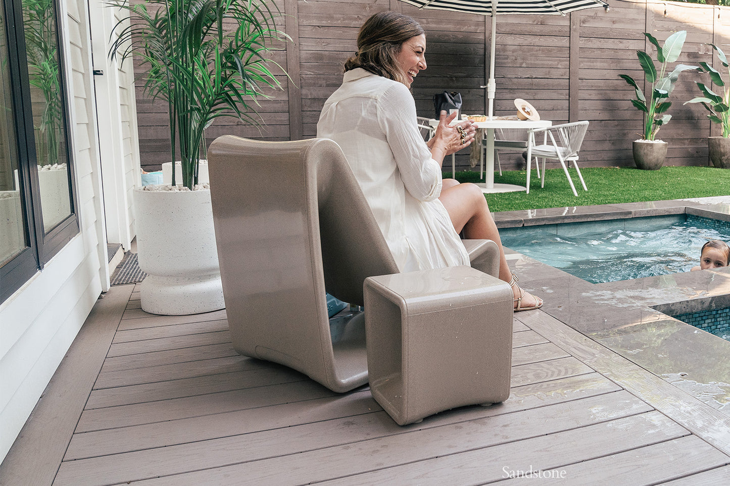 Woman sitting in a Sandstone Tupelo Loop Chair by the pool