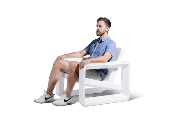Image of a man sitting on the Deck Lounge Chair in the colour Highcloud White made with resin displayed on a white background.