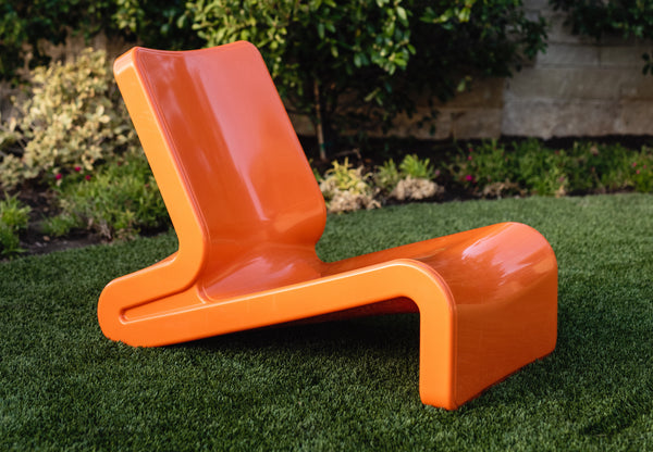 This image shows the Vintage Orange Line Lounge Chair made of premium polyethylene resin, displayed on an outdoor background.