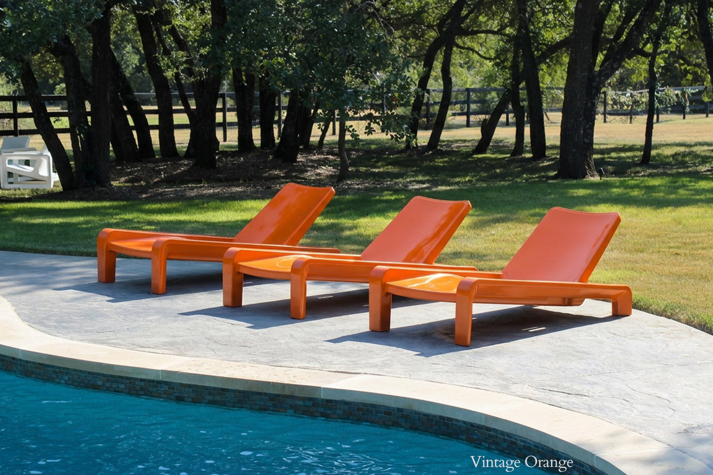 Tupelo Deck Chaise Vintage Orange sitting beside a backyard pool
