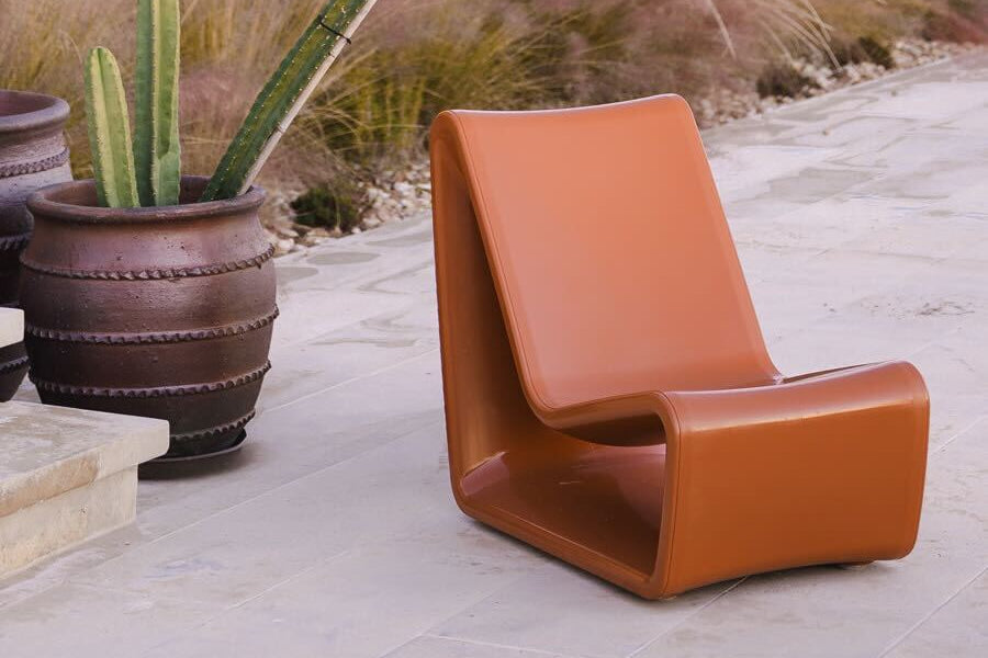 Brown chair on a patio with a gazebo and plants in the background