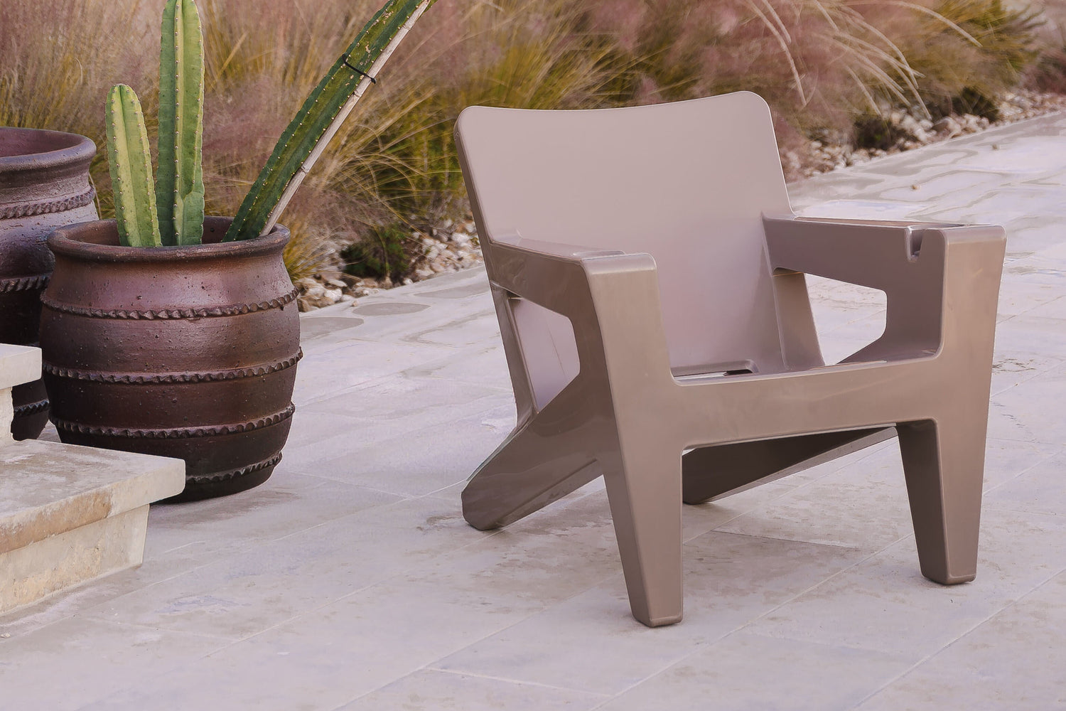 Beige chair on a patio with cacti and a gazebo in the background