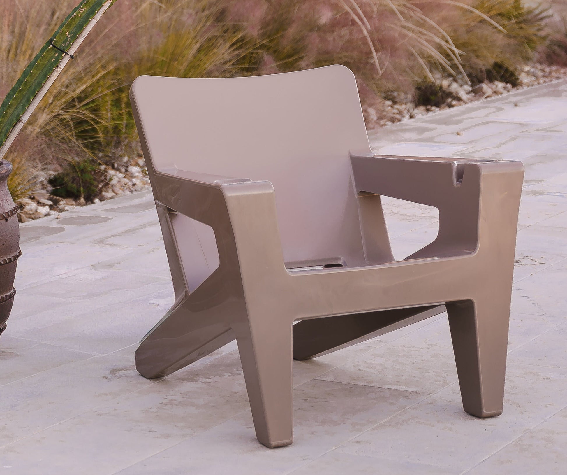 Beige chair on a patio with cacti and a gazebo in the background