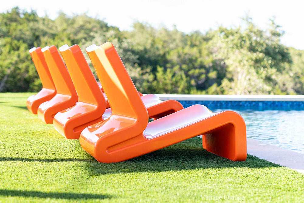 Tupelo Line Chair Vintage Orange beside a pool