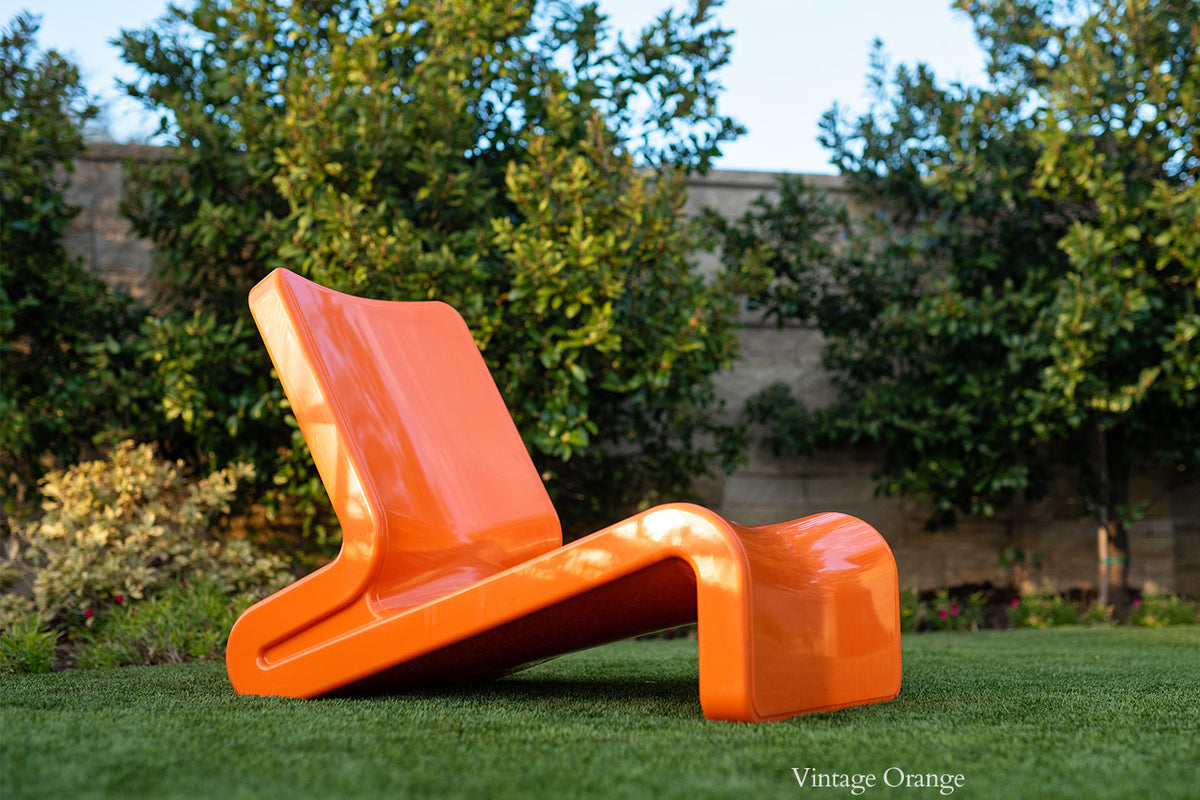 Tupelo Line Chair Vintage Orange displayed in a yard 