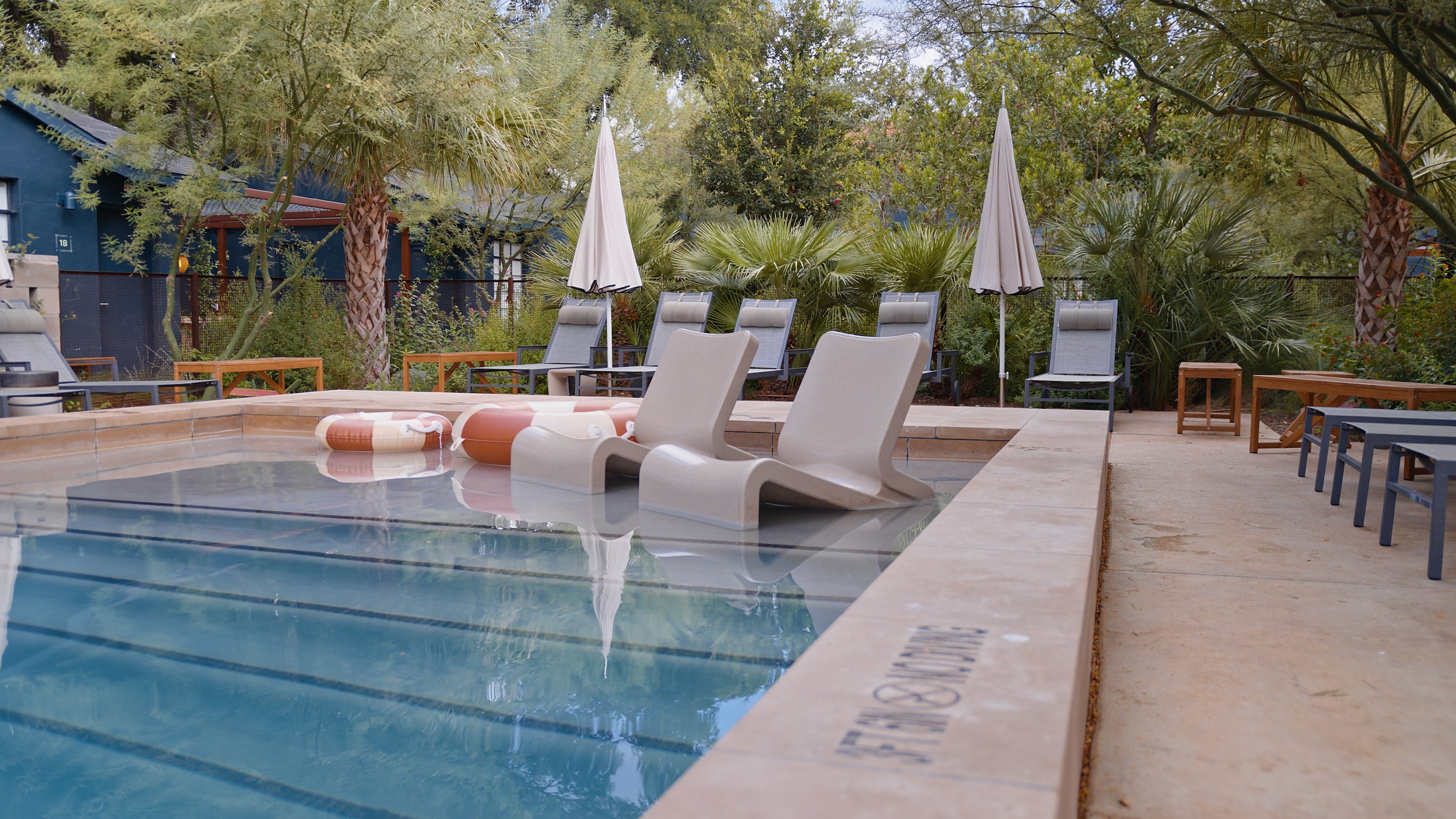 Pool area with lounge chairs, umbrellas, and a wooden deck.