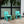Image shows 2 waterproof, UV-resistant, Seafoam Green Fresco Dining Chairs made of resin sitting in an outdoor environment. 