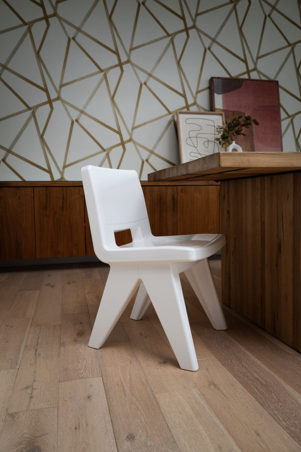 Image shows the Highcloud White Fresco Dining Chair made with resin, indoors on a hardwood floor at an angle near a table.