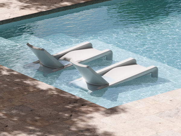 Image of two Deck Chaise Loungers in Highcloud White, made from marine-grade polyethylene sitting outdoors on a pool ledge. 