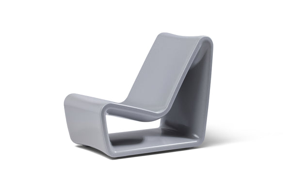 Image of an angled side view of the sleek Concrete Gray Loop Lounge Chair made with polyethylene, shown on a white background.