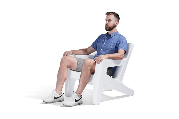 Image of a man sitting on a Bask Lounge Chair in the color Highcloud White, made with polyethylene, on a white background.
