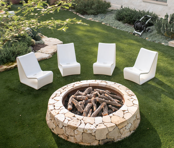 Image of 4 everlasting durable Highcloud White Loop Lounge Chairs made with polyethylene facing a firepit on an outdoor turf.