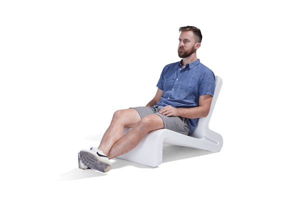 Image shows a man sitting relaxed on the modern, sculptural, Line Lounge Chair made from resin. Great for indoor or outdoor.